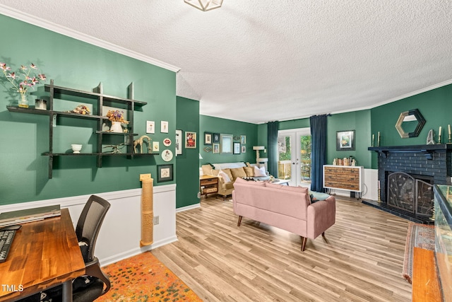 living room featuring light wood-type flooring, a textured ceiling, crown molding, and a fireplace