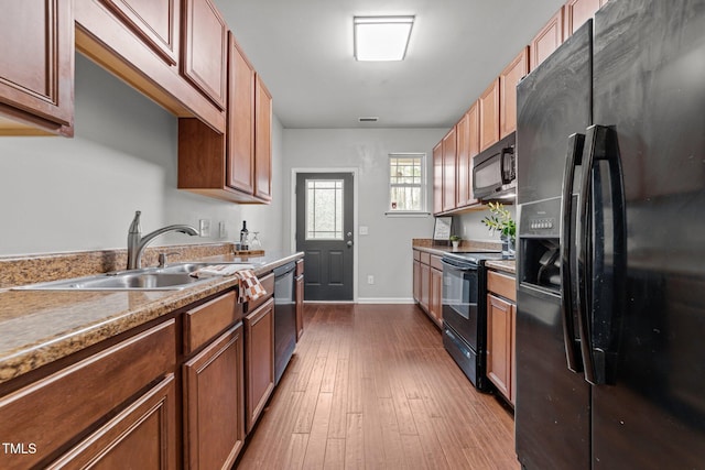 kitchen featuring black appliances, sink, and light hardwood / wood-style floors