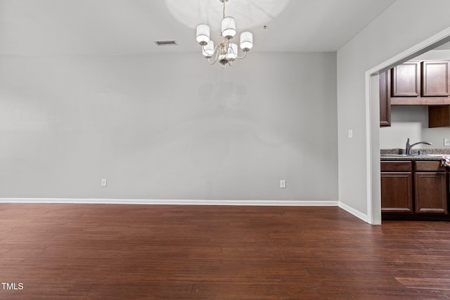 unfurnished dining area featuring dark hardwood / wood-style flooring, sink, and an inviting chandelier