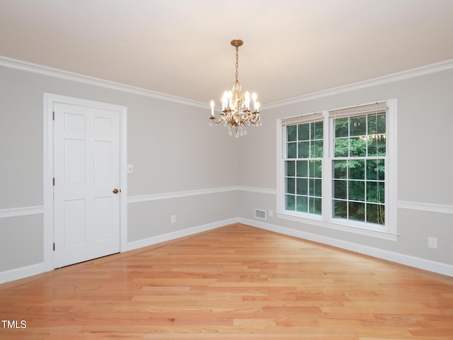 spare room featuring ornamental molding, a chandelier, and light wood-type flooring