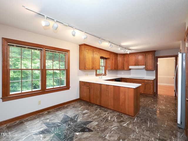 kitchen with stainless steel refrigerator, black electric stovetop, kitchen peninsula, and sink