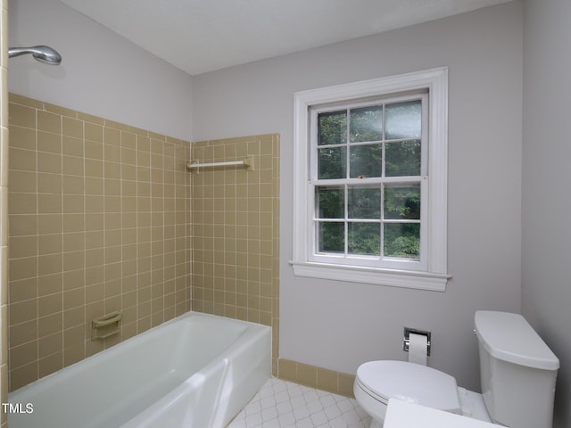 bathroom with tiled shower / bath, tile patterned floors, and toilet