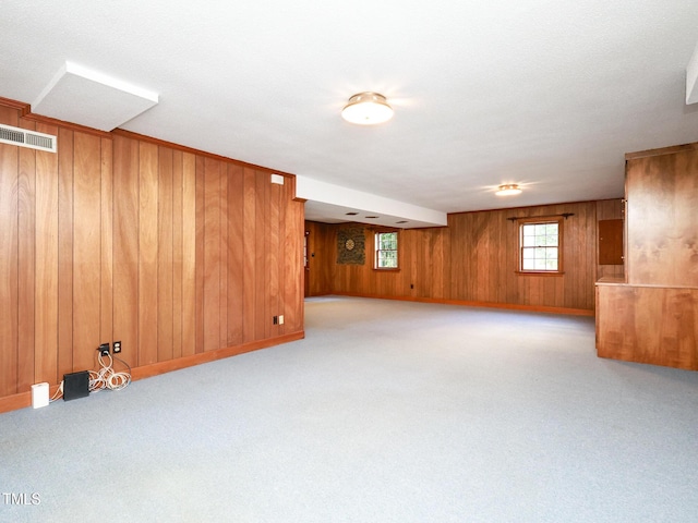 basement featuring light colored carpet and wooden walls