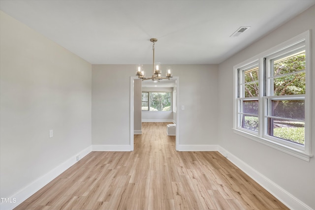 unfurnished dining area with a chandelier and light hardwood / wood-style floors