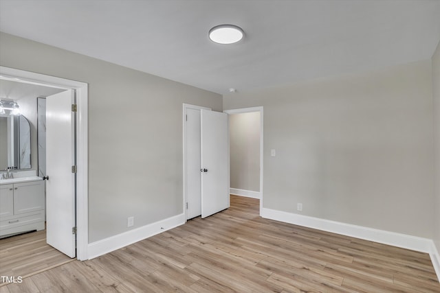 unfurnished bedroom featuring ensuite bath, light wood-type flooring, and sink