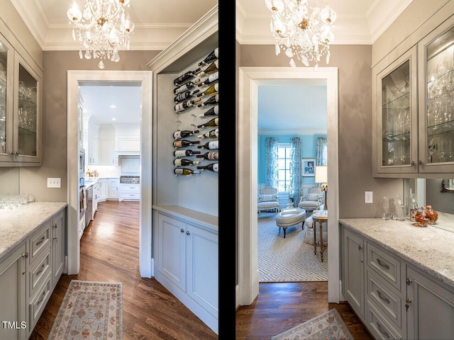 bar featuring pendant lighting, light stone counters, gray cabinets, and an inviting chandelier