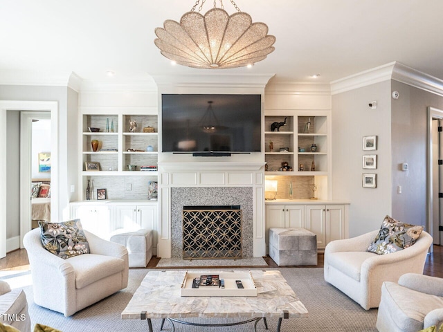 living room with built in shelves, ornamental molding, and light wood-type flooring