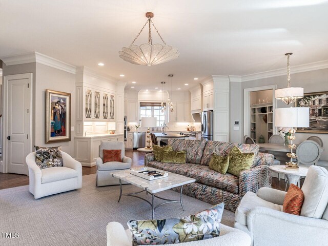 living room featuring an inviting chandelier, crown molding, and light hardwood / wood-style floors