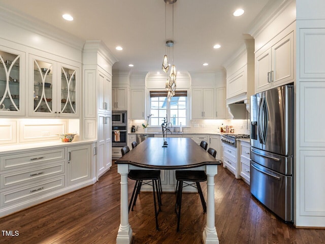 kitchen with white cabinetry, decorative backsplash, appliances with stainless steel finishes, and hanging light fixtures