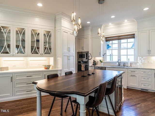 kitchen featuring stainless steel microwave, tasteful backsplash, white cabinetry, sink, and oven