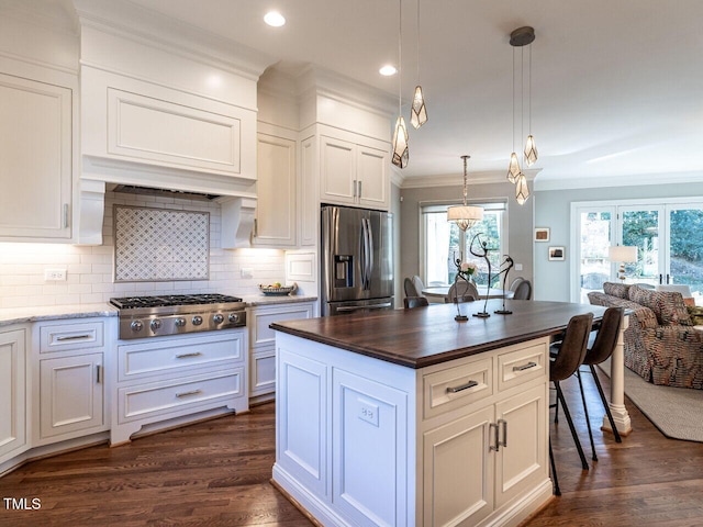 kitchen featuring pendant lighting, ornamental molding, stainless steel appliances, and white cabinets