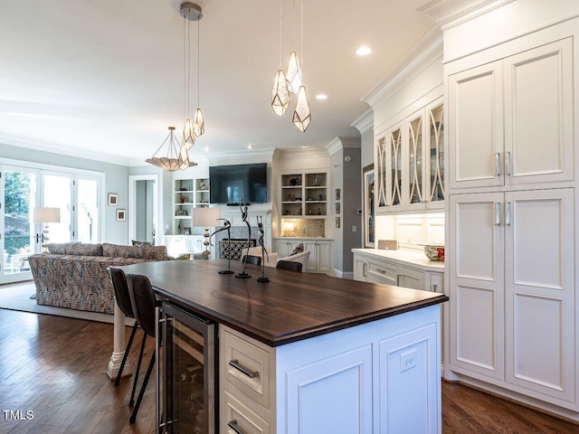 kitchen featuring crown molding, wooden counters, a center island, wine cooler, and white cabinets