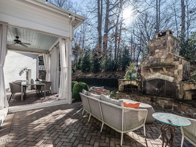 view of patio with ceiling fan and an outdoor living space with a fireplace