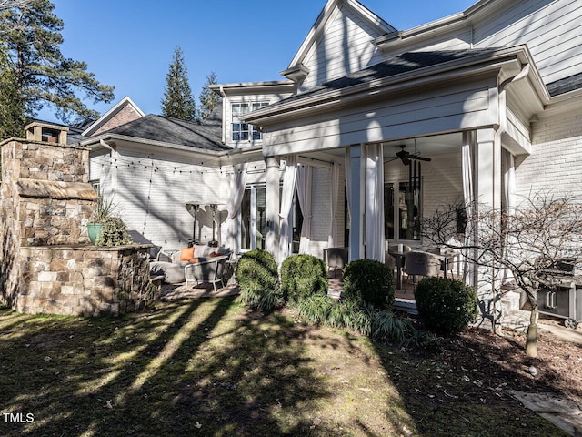 rear view of house featuring a lawn and ceiling fan