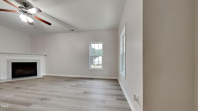 unfurnished living room with ceiling fan, a premium fireplace, and light hardwood / wood-style flooring