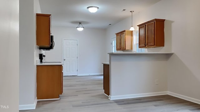 kitchen with pendant lighting, light wood-type flooring, and kitchen peninsula