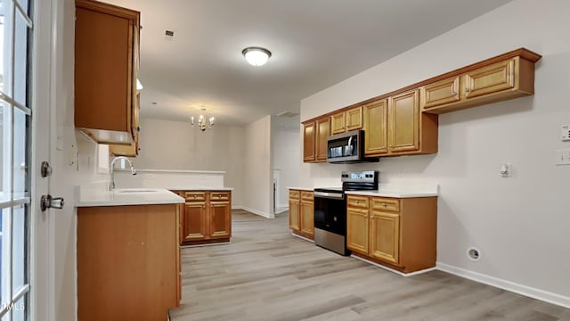 kitchen featuring decorative light fixtures, stainless steel appliances, light hardwood / wood-style floors, and sink