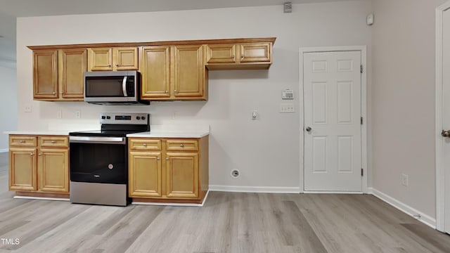 kitchen with appliances with stainless steel finishes and light hardwood / wood-style flooring