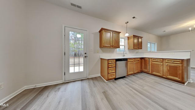 kitchen featuring sink, light wood-type flooring, stainless steel dishwasher, a wealth of natural light, and hanging light fixtures