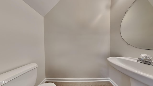 bathroom featuring lofted ceiling, wood-type flooring, toilet, and sink