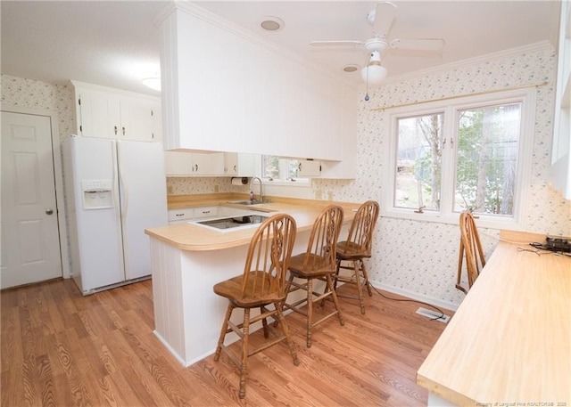 kitchen featuring white cabinetry, a kitchen breakfast bar, light wood-type flooring, kitchen peninsula, and white fridge with ice dispenser