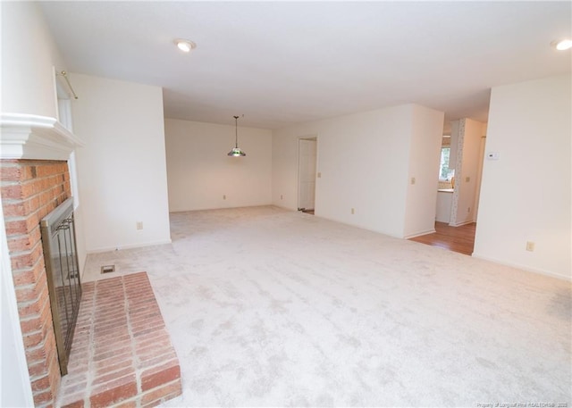 unfurnished living room featuring a fireplace and light colored carpet