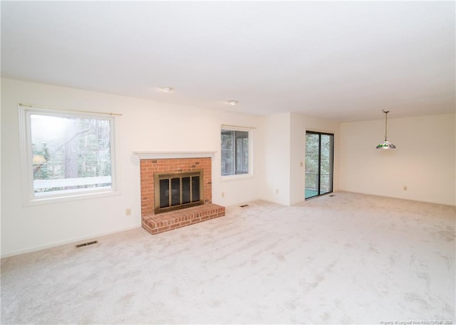 unfurnished living room featuring a brick fireplace and light carpet