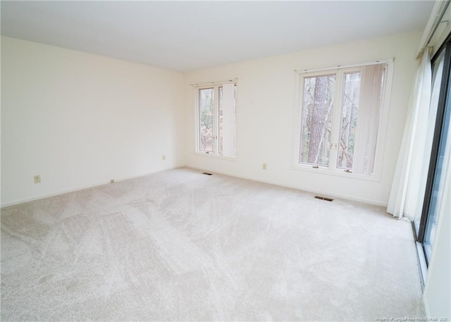 unfurnished room featuring a healthy amount of sunlight and light carpet