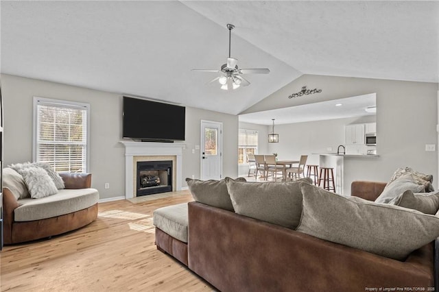 living room with light hardwood / wood-style floors, ceiling fan, lofted ceiling, and sink