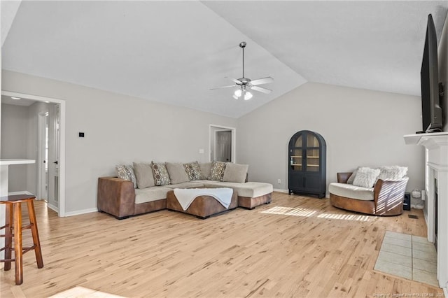 living room featuring light hardwood / wood-style floors, ceiling fan, vaulted ceiling, and a tiled fireplace