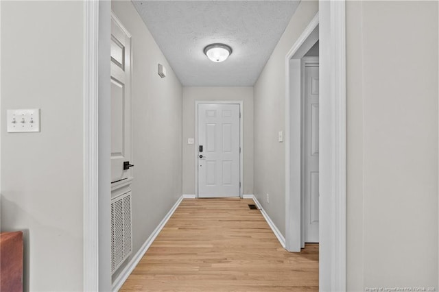 doorway to outside with a textured ceiling and light hardwood / wood-style floors