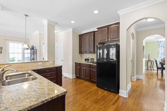 kitchen featuring ornamental molding, black fridge, sink, and dark brown cabinetry