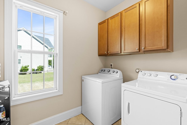 laundry area with cabinets, a healthy amount of sunlight, washer and dryer, and light tile patterned floors