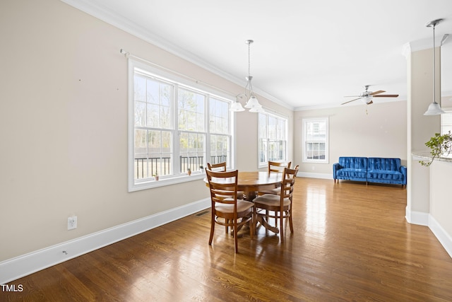 dining space featuring dark hardwood / wood-style flooring, crown molding, and ceiling fan with notable chandelier