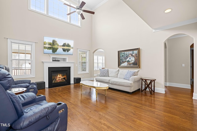 living room with ceiling fan, ornamental molding, hardwood / wood-style floors, and a high ceiling