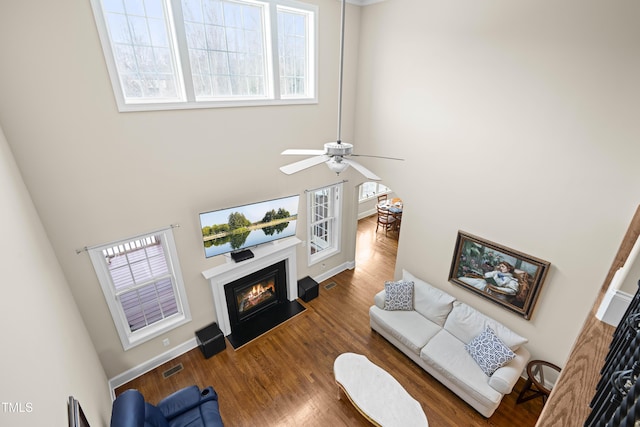 living room featuring a healthy amount of sunlight, dark wood-type flooring, and a towering ceiling