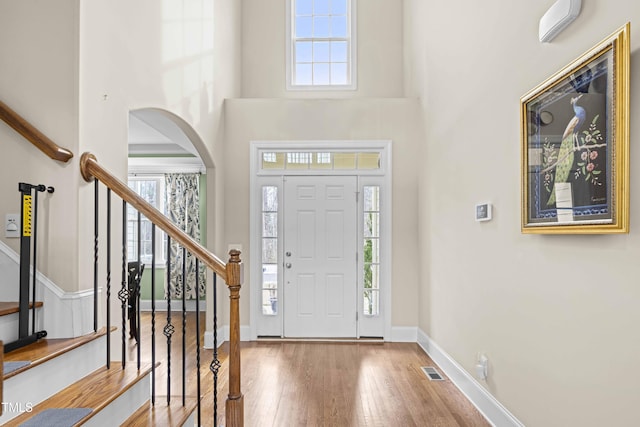 entrance foyer with a towering ceiling, plenty of natural light, and hardwood / wood-style floors