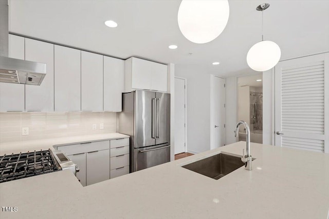 kitchen featuring a sink, light countertops, appliances with stainless steel finishes, tasteful backsplash, and decorative light fixtures