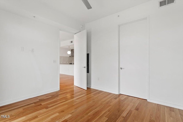 spare room with light wood-style floors, visible vents, and baseboards