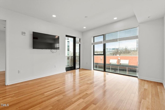 unfurnished living room with a healthy amount of sunlight, light wood-style floors, baseboards, and recessed lighting