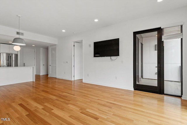 unfurnished living room featuring light wood finished floors, baseboards, visible vents, and recessed lighting