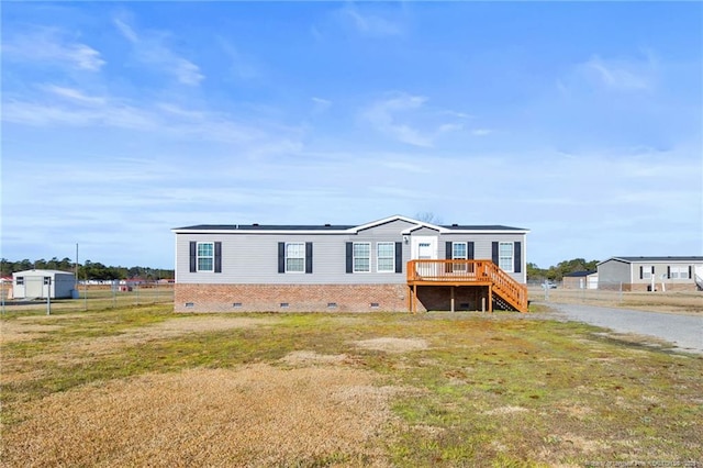 manufactured / mobile home featuring a wooden deck and a front lawn