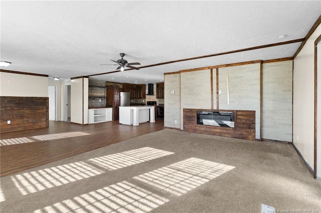 unfurnished living room featuring dark carpet, a textured ceiling, and ceiling fan