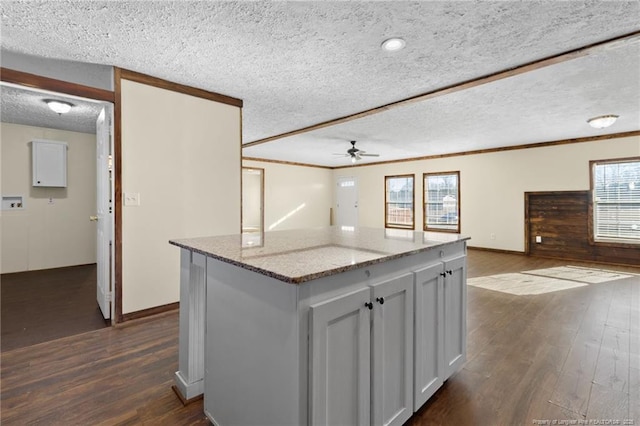 kitchen featuring light stone countertops, ceiling fan, dark hardwood / wood-style floors, a kitchen island, and a textured ceiling