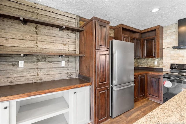 kitchen with wall chimney exhaust hood, dark hardwood / wood-style floors, stainless steel fridge, decorative backsplash, and black range with electric cooktop