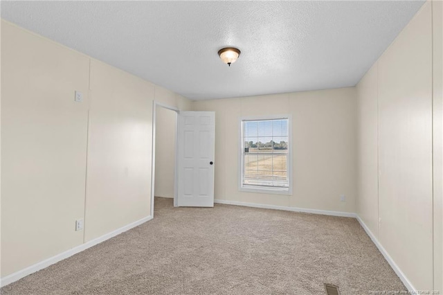 carpeted empty room featuring a textured ceiling