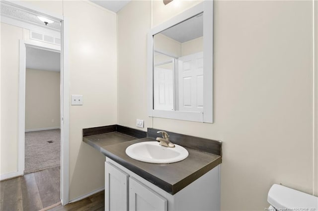 bathroom with toilet, vanity, and hardwood / wood-style flooring