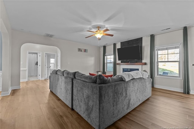 living room with ceiling fan, a large fireplace, and light hardwood / wood-style flooring