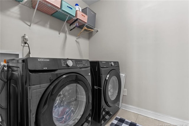 clothes washing area featuring light tile patterned floors and washing machine and clothes dryer