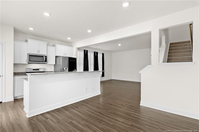 kitchen featuring a kitchen island with sink, appliances with stainless steel finishes, light stone countertops, dark hardwood / wood-style flooring, and white cabinetry